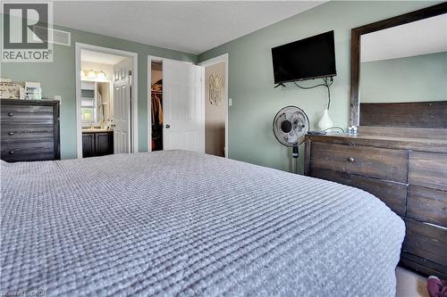 Bedroom featuring light green walls, white trim, and direct access to a bathroom with a vanity and mirror - 60 Featherstone Street, Kitchener, ON - Indoor Photo Showing Bedroom