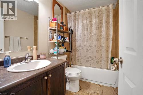Bathroom featuring a white vanity sink, dark wood-finish cabinetry, a full-size mirror, and a tub with tiled surround - 60 Featherstone Street, Kitchener, ON - Indoor Photo Showing Bathroom