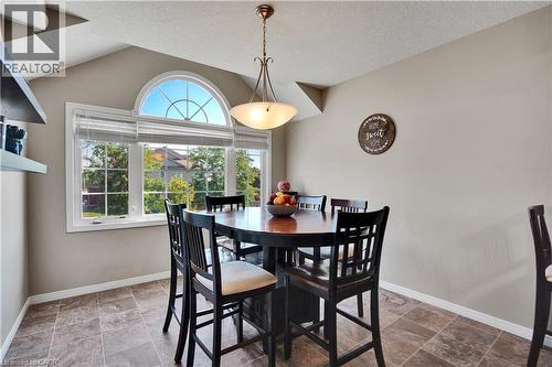 Dining area featuring a large multi-pane window with an arched transom, a semi-flush mount chandelier, and tile flooring - 60 Featherstone Street, Kitchener, ON - Indoor Photo Showing Dining Room