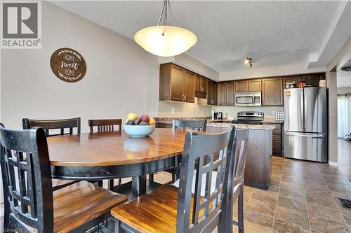 Eat-in kitchen featuring dark wood cabinetry, stainless steel appliances, and a tiled backsplash - 60 Featherstone Street, Kitchener, ON - Indoor Photo Showing Dining Room