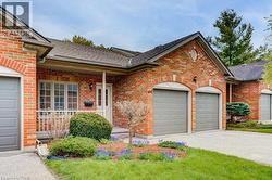 Brick exterior with dual garage doors, a covered front porch, and a landscaped garden - 