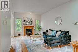 Living area featuring a fireplace with a detailed wood mantel, hardwood flooring, and multiple windows - 