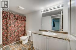 Bathroom featuring a single vanity with a laminate countertop, an undermount sink with a chrome faucet, and a large mirror with strip lighting - 