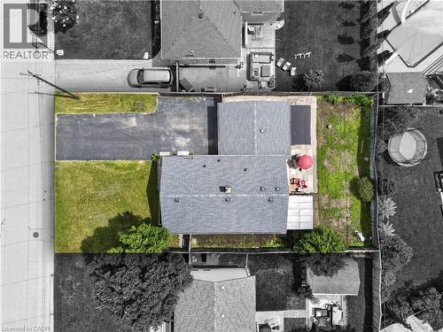 Property featuring a shingle roof, a paved driveway, and a partially fenced rear yard with a grass lawn - 236 Hammersmith Court, Burlington, ON - 