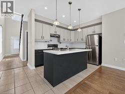 Contemporary kitchen featuring light gray upper cabinetry, dark gray lower cabinetry, and a white subway tile backsplash - 
