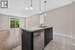 Kitchen island with integrated sink and dishwasher, featuring pendant lighting and tile flooring - 