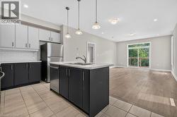Modern kitchen featuring two-tone cabinetry, stainless steel appliances, a subway tile backsplash, and an island with an undermount sink - 