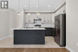 Contemporary kitchen featuring a dark-toned island with an integrated sink, white quartz countertops, and three pendant lights - 
