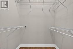 Walk-in closet featuring wire shelving, hanging rods, and wood-finish flooring with white baseboards - 
