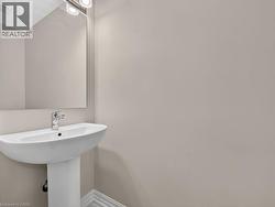 Pedestal sink with chrome faucet, large rectangular mirror, and an overhead vanity light fixture - 