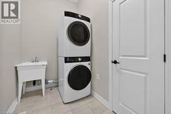Laundry area featuring a utility sink, light-toned wall paint, and tile flooring - 