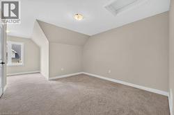 Carpeted room featuring sloped ceilings, a window with exterior views, and a ceiling-mounted light fixture - 