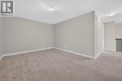 Spacious carpeted room featuring light gray walls, white baseboards, and a white ceiling with a flush-mount light fixture - 