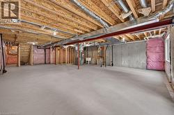 Expansive lower level featuring a concrete floor, exposed wood ceiling joists, and structural I-beam - 