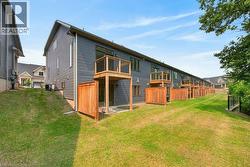 Rear exterior featuring dark horizontal siding, private wood-fenced patios, and individual upper-level balconies with wood decking and metal railings - 