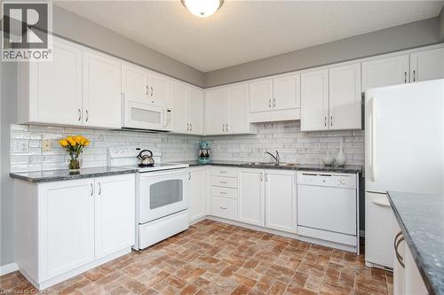 Kitchen featuring white cabinetry, dark speckled countertops, white subway tile backsplash, and brick-patterned flooring - 38 David Bergey Drive, Kitchener, ON - Indoor Photo Showing Kitchen