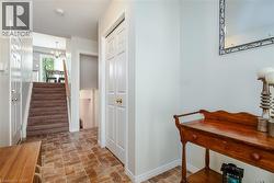 Tiled entryway with a paneled closet door and a carpeted staircase leading to an upper level - 