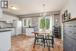 Kitchen and dining area featuring white cabinetry, dark countertops, a tile backsplash, and a sliding glass door to an exterior deck - 