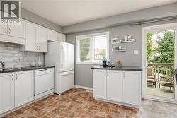 Kitchen featuring white cabinetry, a gray subway tile backsplash, and dark countertops - 