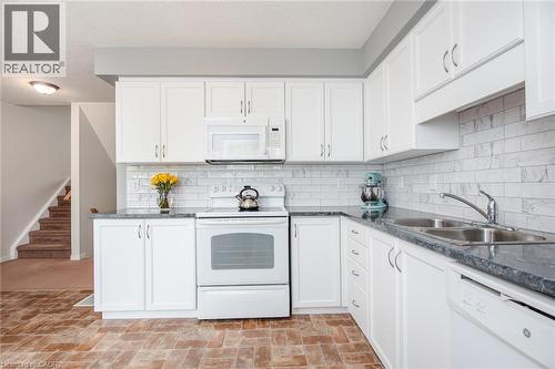 Kitchen featuring white cabinetry, grey countertops, white subway tile backsplash, and wood-finish flooring - 38 David Bergey Drive, Kitchener, ON - Indoor Photo Showing Kitchen With Double Sink