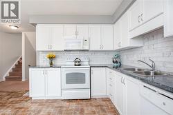Kitchen featuring white cabinetry, grey countertops, white subway tile backsplash, and wood-finish flooring - 