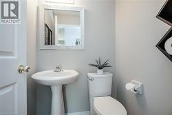Pedestal sink with chrome faucet, complemented by a decorative mirror and overhead lighting - 
