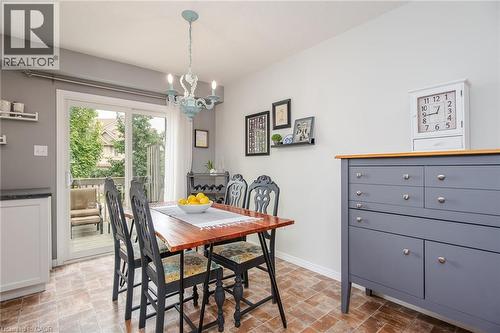 Dining area featuring wood-finish flooring, a sliding glass door providing exterior access, and a light blue chandelier - 38 David Bergey Drive, Kitchener, ON - Indoor Photo Showing Dining Room