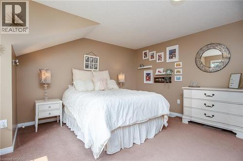 Carpeted room with a vaulted ceiling, neutral wall paint, built-in wall sconce, and ceiling light fixture - 38 David Bergey Drive, Kitchener, ON - Indoor Photo Showing Bedroom