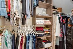 Custom closet organization system featuring wood-finish shelving, multiple hanging rods, and integrated storage compartments - 