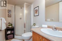 Full bathroom featuring a glass-enclosed shower with textured privacy panels, a light wood-finish vanity with a built-in sink, a neutral-toned countertop, and tile flooring - 