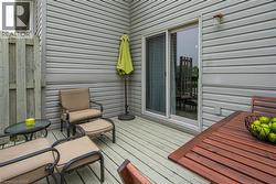 Private outdoor deck featuring horizontal siding, a sliding glass door, and exterior lighting - 