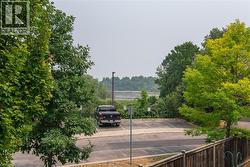 Paved parking lot surrounded by mature trees, with a wooden fence in the foreground - 