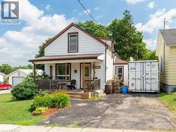 White siding exterior with dark trim and a covered front porch featuring wooden railings - 