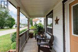 Covered front porch featuring wooden posts, railing, and flooring - 