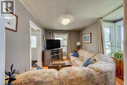 Living room featuring wood-finish flooring and a bay window with natural light - 