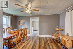 Dining area featuring wood-finish flooring, a white window frame, and a ceiling fan with light fixture - 