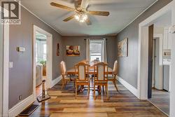 Dining area featuring a ceiling fan with light fixture, wood-finish flooring, and white trim - 