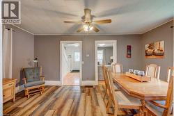 Dining area featuring variegated wood-finish flooring, light gray walls, and a ceiling fan with integrated lighting - 