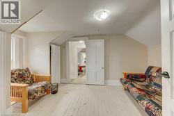 Bright room featuring painted wood-finish flooring, white walls, a flush-mount ceiling light fixture, and a doorway leading to an additional space - 