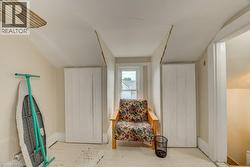 Attic space featuring a window, painted wood flooring, and built-in vertical panel cabinetry - 