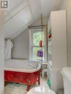 Freestanding clawfoot bathtub featuring a red finish and chrome fixtures - 