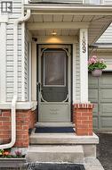 Welcoming front entry with a decorative storm door, concrete steps, brick accents, and vertical siding - 