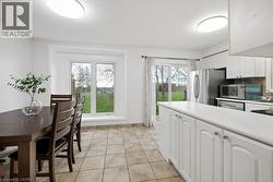 Spacious kitchen and dining area with tile flooring, white cabinetry, and stainless steel appliances - 