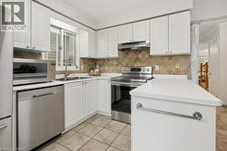 Kitchen featuring white cabinetry, stainless steel appliances, mosaic tile backsplash, white countertops, and tiled flooring - 