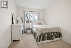 Bedroom featuring neutral-toned walls, a window with curtains, and carpeting - 