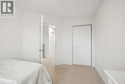Neutral tone carpeting complemented by white walls, a white bi-fold closet door, and a white interior door with a silver knob - 