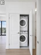 Dedicated laundry closet featuring a stacked washer and dryer, white paneled doors, and light wood-finish flooring - 