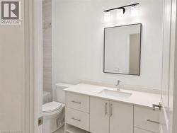 Modern bathroom featuring a white vanity with an integrated sink, a light-toned countertop, and a contemporary black-framed mirror - 