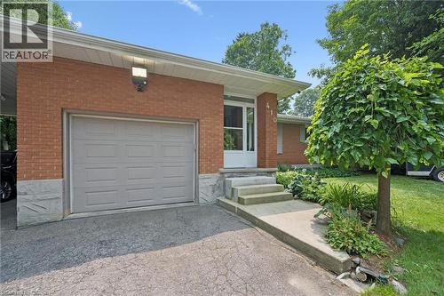 Brick facade residence featuring a single-car garage with a panel door and large LED exterior lighting - 410 Avenue Road, Cambridge, ON - Outdoor With Exterior