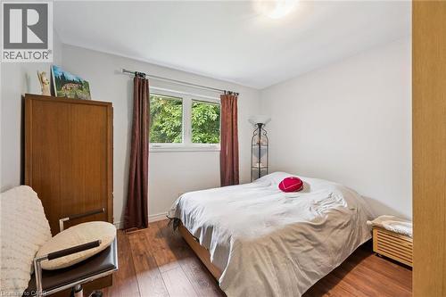 Room featuring wood-finish flooring, a double window with exterior tree scenery, white wall paint, and a built-in light fixture - 410 Avenue Road, Cambridge, ON - Indoor Photo Showing Bedroom